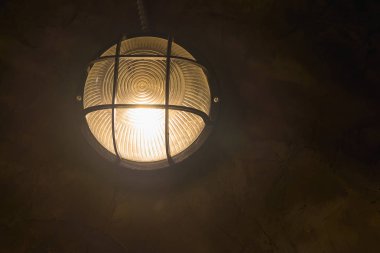 Koyu arka plan üzerinde parlayan tungsten Duvar lambası.