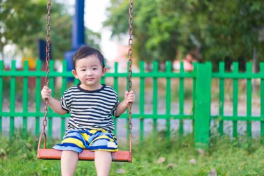 Genç Asyalı çocuk oyun bahçesi altında sallanan bir demir