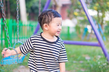 Genç Asyalı çocuk oyun bahçesi altında sallanan bir demir