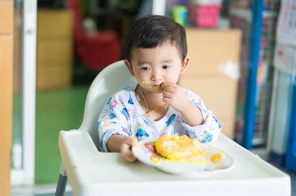 Азиатский ребенок ест торт со сливками на лице . — стоковое фото