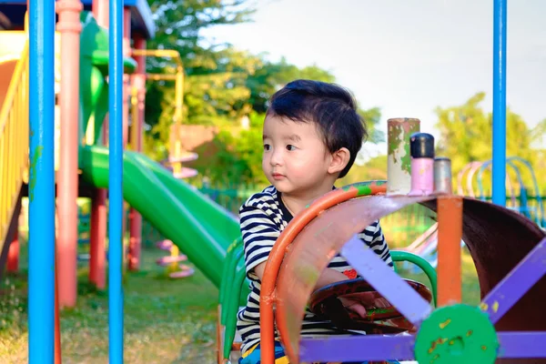 Joven asiático jugar un tren de hierro balanceo en el patio de recreo und — Foto de Stock
