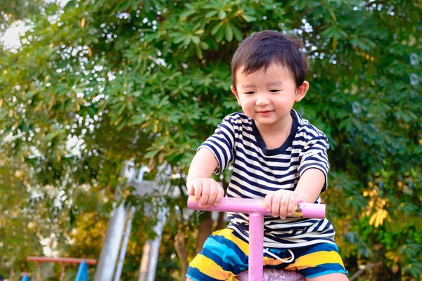 Asian kid riding seesaw board at the playground under sunlight, — Stock Photo, Image