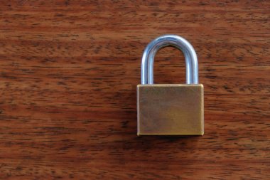 Üzerinde kahverengi ahşap masa arka plan asma kilit.