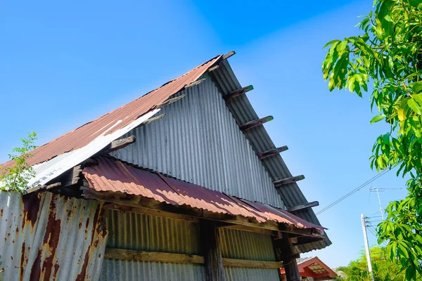 Viejo oxidado galvanizado hoja (hoja de zinc) edificio con árbol verde — Foto de Stock