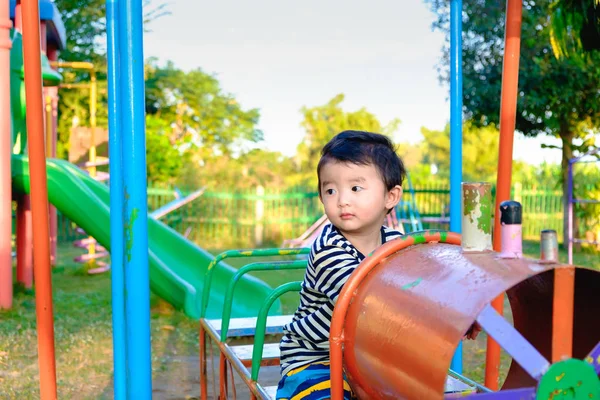 Unga asiatiska pojke spela en järn tåg svängande på lekplats und — Stockfoto