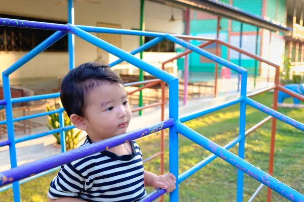 Chłopiec azjatyckich powiesić metalowy drążek na plac zabaw. — Zdjęcie stockowe