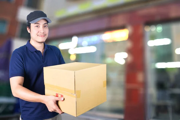 Hombre de entrega asiática con caja de cartón sobre fondo borroso . — Foto de Stock