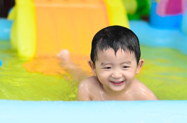 Asyalı çocuk şişme bebek yüzme havuzunda sıcak yaz oynarken