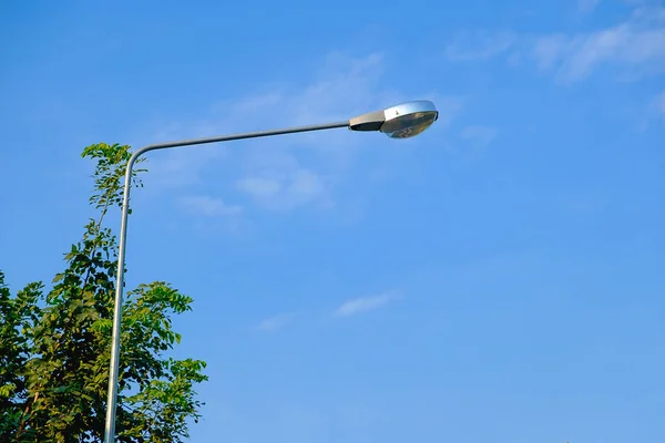 Lámpara de calle contra el cielo azul y el fondo del árbol . —  Fotos de Stock