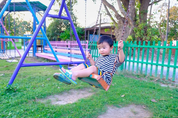 Anak Asia yang sedih memainkan besi berayun di taman bermain di bawah s — Stok Foto