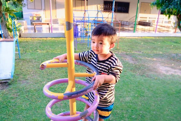 Niño pequeño y activo jugando a escalar metal de primavera en el patio de la escuela —  Fotos de Stock