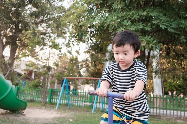 Lycklig unge spela gungbräda vackla i lekplats, färgton, grunt — Stockfoto