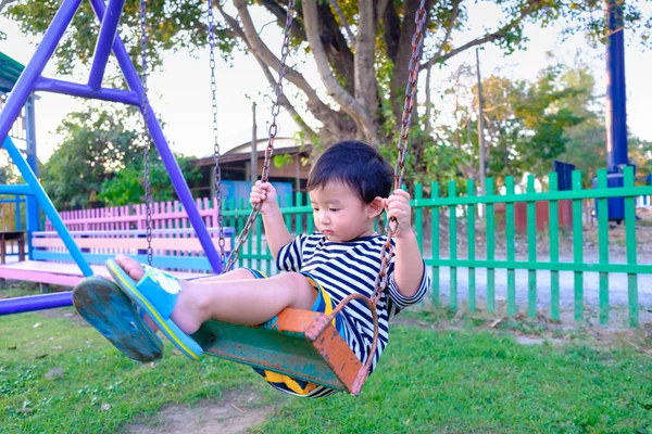 Young Asian boy play a iron swinging at the playground under the — Stock Photo, Image