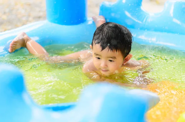 Niño asiático jugando en la piscina inflable del bebé en verano caliente — Foto de Stock