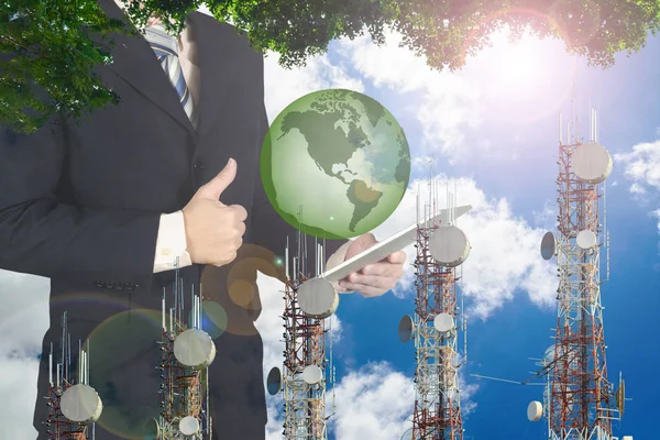 Double exposure of businessman using tablet with green earth pla