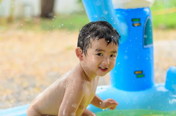 Niño asiático jugando en la piscina inflable del bebé en verano caliente — Foto de Stock