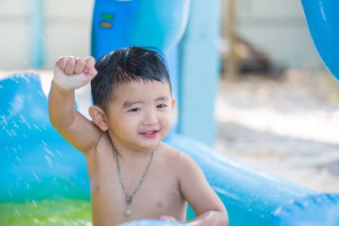 Asyalı çocuk şişme bebek yüzme havuzunda sıcak yaz oynarken