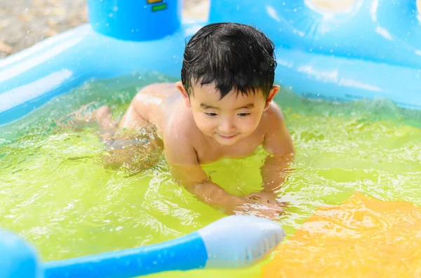 Niño asiático jugando en la piscina inflable del bebé en verano caliente — Foto de Stock