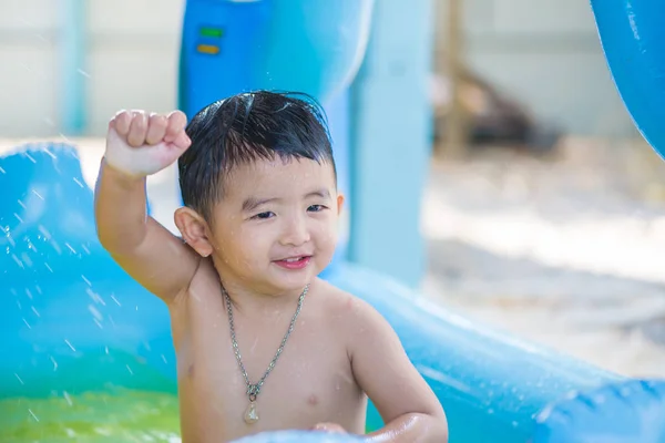 Niño asiático jugando en la piscina inflable del bebé en verano caliente — Foto de Stock