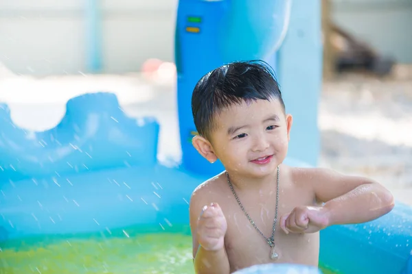 Niño asiático jugando en la piscina inflable del bebé en verano caliente — Foto de Stock