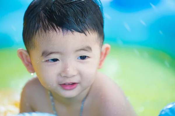 Asian kid playing in inflatable baby swimming pool on hot summer — Stock Photo, Image