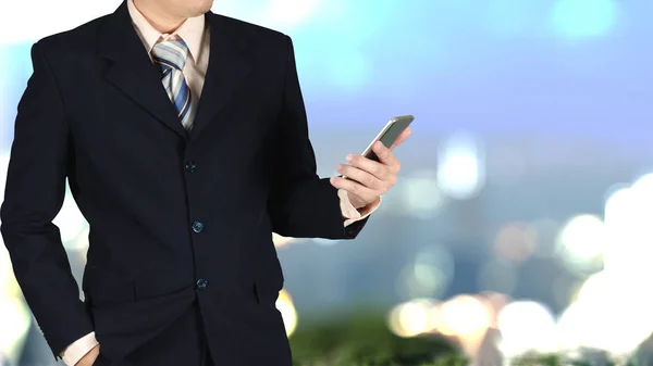 Dubbel exponering av affärsmannen håller smarta telefonen på suddig ci — Stockfoto
