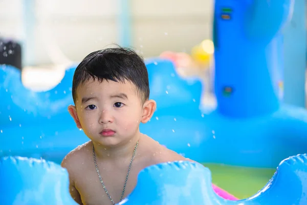 Triste asiático niño jugando solo en inflable bebé piscina . — Foto de Stock