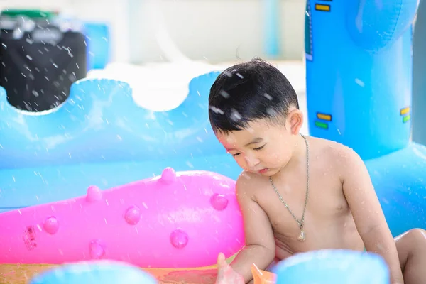 Niño asiático jugando en la piscina inflable del bebé en verano caliente — Foto de Stock