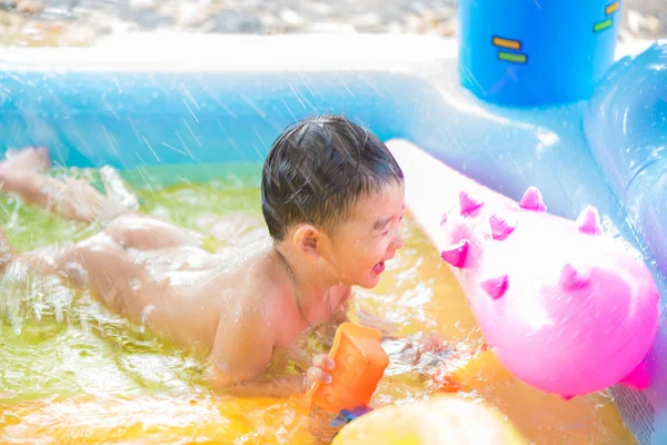 Niño asiático jugando en la piscina inflable del bebé en verano caliente — Foto de Stock