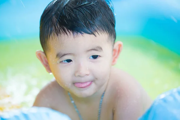 Asian kid playing in inflatable baby swimming pool on hot summer — Stock Photo, Image