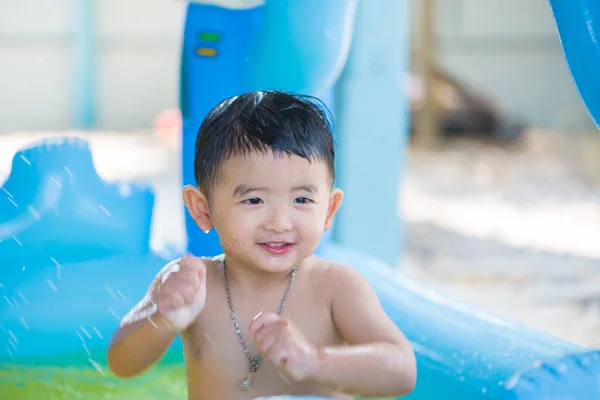 Asian kid playing in inflatable baby swimming pool on hot summer — Stock Photo, Image