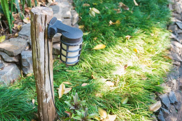 Lampe an einer kurzen Holzstange mit Gras im Garten. — Stockfoto