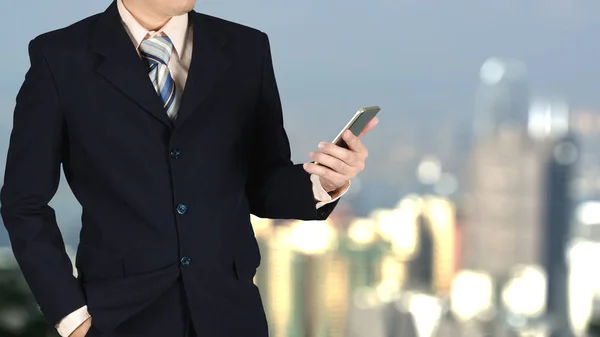 Dubbel exponering av affärsmannen håller smarta telefonen på suddig ci — Stockfoto