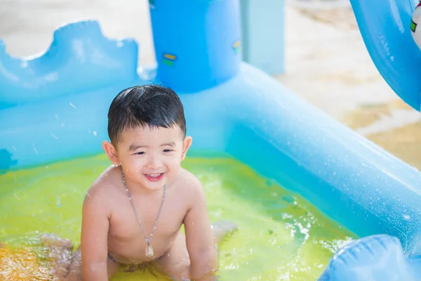 Niño asiático jugando en la piscina inflable del bebé en verano caliente — Foto de Stock