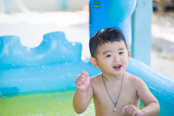 Niño asiático jugando en la piscina inflable del bebé en verano caliente — Foto de Stock