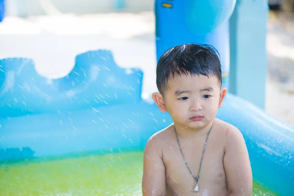 Triste asiático niño jugando solo en inflable bebé piscina . — Foto de Stock