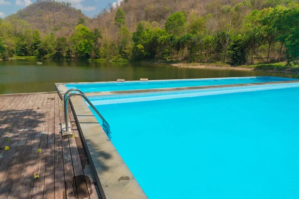 蓝色泳池与湖山附近的木地板 — 图库照片