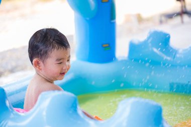 Asyalı çocuk şişme bebek yüzme havuzunda sıcak yaz oynarken