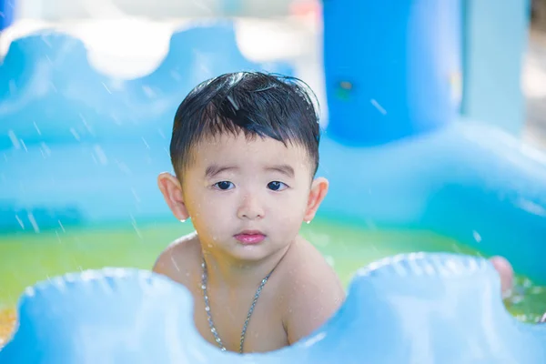 Niño asiático jugando en la piscina inflable del bebé en verano caliente — Foto de Stock