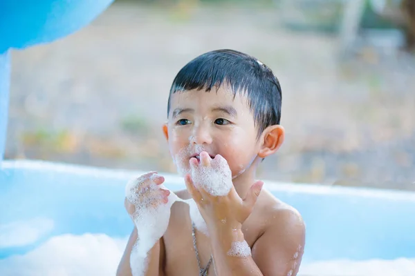 アジアの少年の水と泡で遊んでの膨脹可能な赤ん坊のプールに — ストック写真