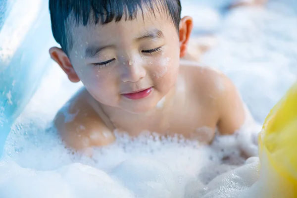 Menino asiático brincando com água e espuma na piscina inflável do bebê no — Fotografia de Stock