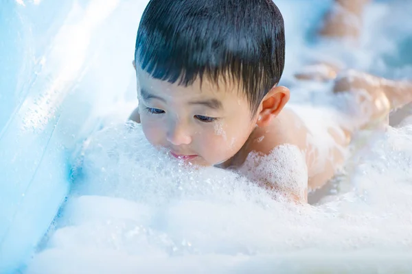 Asiático chico jugando con agua y espuma en inflable bebé piscina en — Foto de Stock