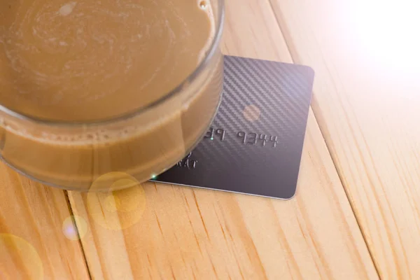 Кредитная карта и стакан горячего кофе на деревянном столе, мягкий тон . — стоковое фото