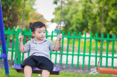 Genç Asyalı çocuk oyun bahçesi altında sallanan bir demir