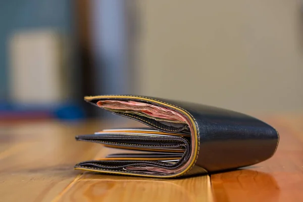Черные мужчины кожаный бумажник с банкнотами на деревянном столе в винте — стоковое фото