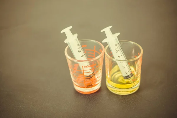 Seringue avec sirop de médicament dans une mesure pharmaceutique en verre — Photo