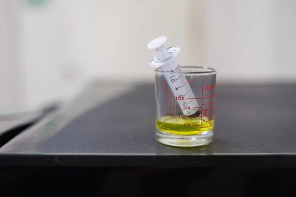 Seringa com xarope de medicamento em um copo farmacêutico de medição — Fotografia de Stock