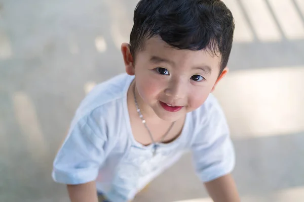 Pequeño niño asiático jugando y sonriendo en el patio de recreo bajo el — Foto de Stock