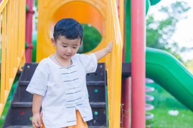 Asyalı çocuk parkta merdivenlerden aşağı gider.