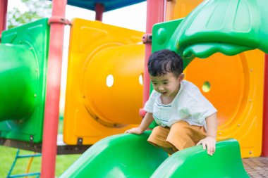 Küçük Asyalı Çocuk Bahçesi sunli altında slayt oynayan